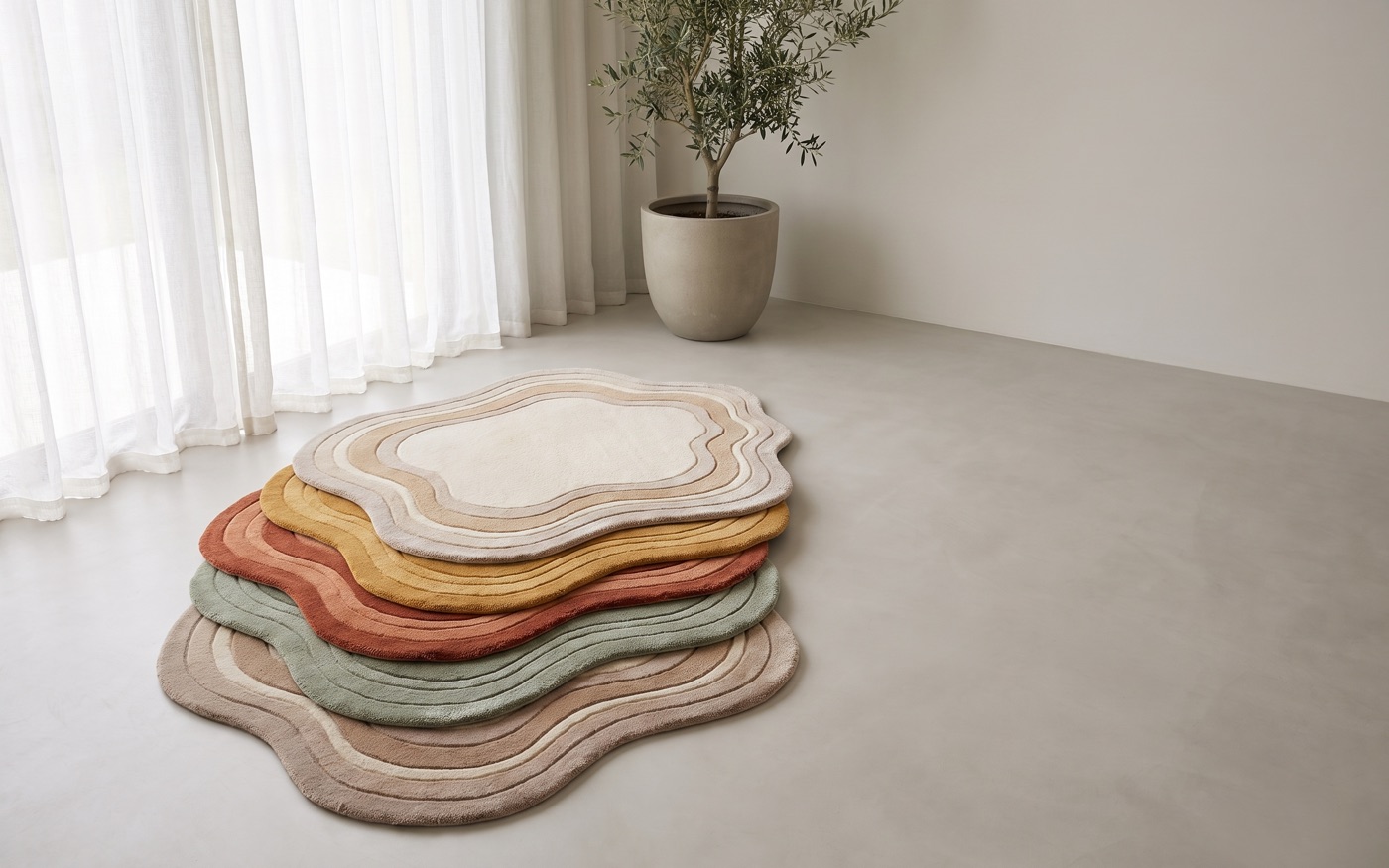 Layered hand-tufted rugs with organic scalloped edges in cream, ochre, terracotta and sage